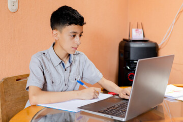 Hispanic boy on computer doing homework - boy studying from home - online classes