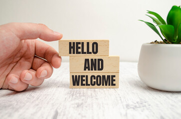 Hello and welcome symbol. Concept words Hello and welcome on wooden blocks. Businessman hand.
