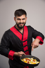 Man holding vegetables on dark pan