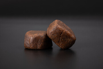 dark lumps of cannabis Moroccan hashish with high thc on a black background. - obrazy, fototapety, plakaty