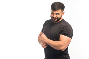 Sportive man in black shirt demonstrating his arm muscles