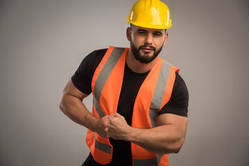 Engineer in orange uniform and yellow helmet with big muscles