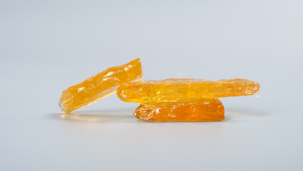 cannabis wax with high thc on gray background, pieces of golden clean marijuana concentrate.