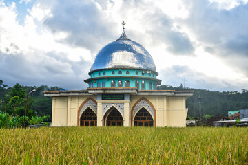 view of mosque against cloudy with corn field foreground in the village