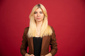 Fototapeta premium Office employee in brown jacket posing on red background