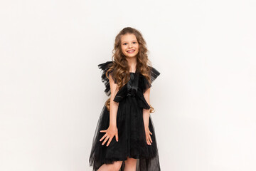 A charming little girl with curly hair and a fluffy dress on a white isolated background. A beautiful princess on Black Friday.