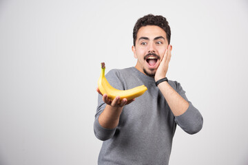 Brunette man looking at banana happily