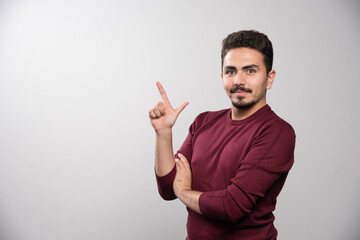 Fototapeta premium A young brunette man showing a finger up and posing