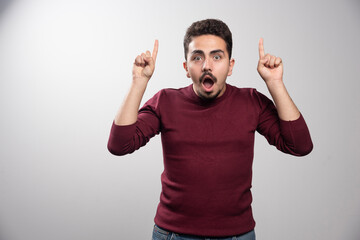 Fototapeta premium A shocked brunette man showing fingers up and posing