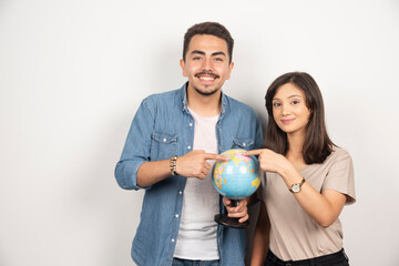 Man and woman posing with globe on white background