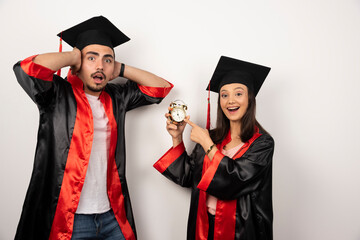 Fresh graduates in gown showing time on white background