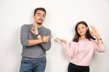 Happy couple pointing at themselves on white background