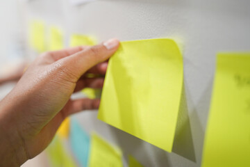 Hand holding a yellow notepaper for her opinion