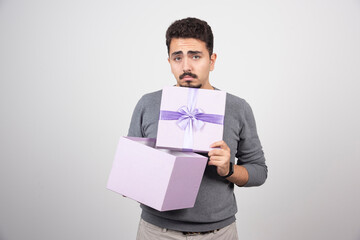 Sad man opening a purple box over a white wall