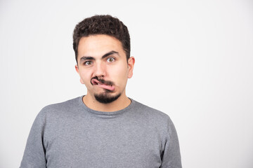 Fototapeta premium A young man doing a funny face over a white wall