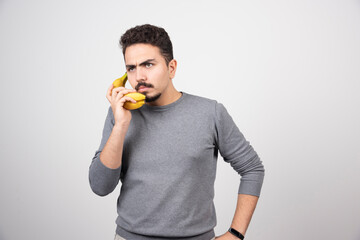 A young man model holding a banana as a phone