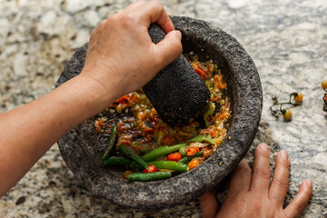 Hispanic person makes a traditional molcajete sauce