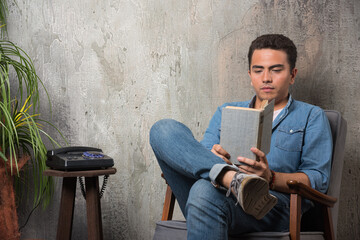 Young man reading a book and sitting on chair