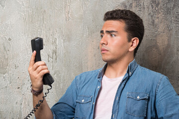 Naklejka premium Photo of wondering man talking on phone and sitting on chair