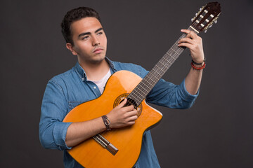 Young musician holding a beautiful guitar on black background