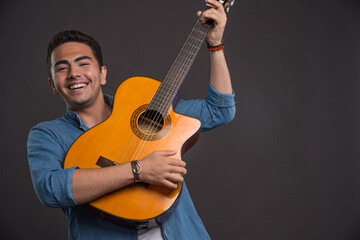 Young musician playing the guitar on black background
