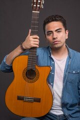 Young man holding a beautiful guitar on black background