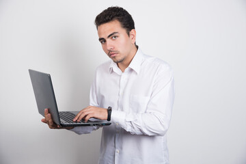 Solemn businessman using laptop on white background