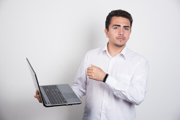 Solemn businessman with laptop standing on white background