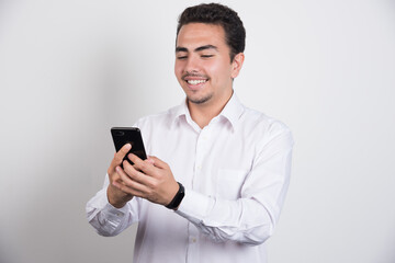 Obraz na płótnie Canvas Smiling businessman looking at telephone on white background