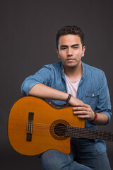 Serious man holding a guitar on dark background