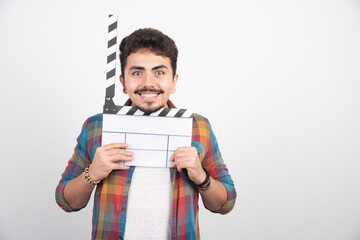 A filmmaker holding blank clapper board, opening it and laughing loud through it