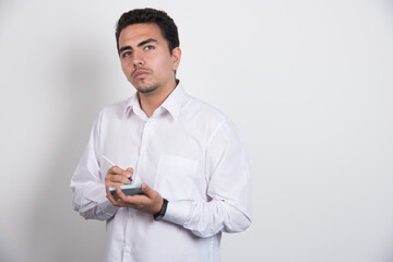 Young businessman writing on white background