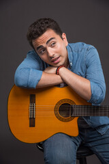 Obraz premium Brunette man with guitar looking his side on dark background