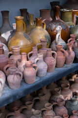 Fototapeta na wymiar Closeup of many unique handmade colorful clay jugs and vases of various shapes on shelf in local market. Lot of handicraft ceramic pots. 