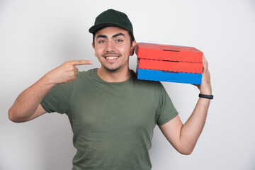 Deliveryman pointing at three boxes of pizza on white background