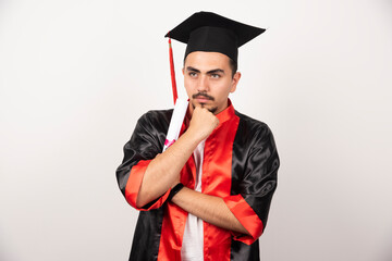 Young male student with diploma thinking on white background