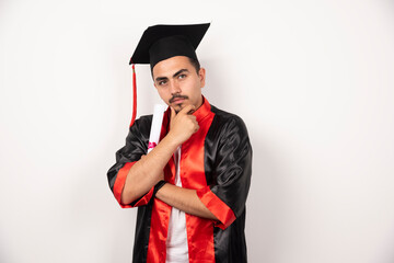 Young male student with diploma thinking on white background