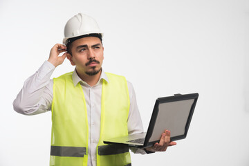 Engineer in uniform holding a laptop and thinking