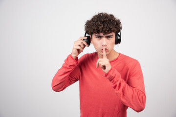 Fototapeta na wymiar Young man listening to music with headphones and making silence sign