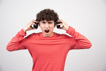 Young man listening to music with headphones angrily