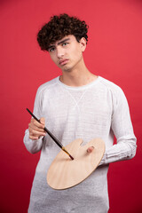 Portrait of a young male artist holding palette and brushes