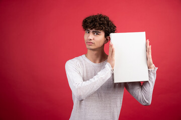 Young boy holding empty canvas on red background