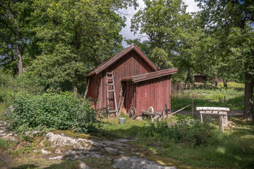Old farm shed with privy, grindstone and chopping block in a park a sunny day in Stockholm