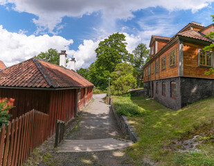 Alley between old 1700s red wood houses with cumulus clouds a sunny summer day in Stockholm