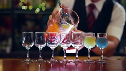 4K Male bartender preparing and pouring mixed colorful cocktail drink from shaker into cocktail glass on bar counter at pub. Professional barman making alcoholic drink serving to customer at nightclub