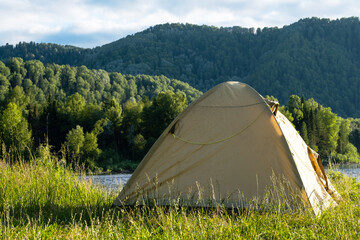 Tourist tent on river bank. Camping tent near mountain river. Local tourism, weekend at nature.