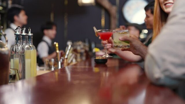 4K Group of People man and woman enjoy hangout nightlife celebrating party drinking cocktail beverage at luxury bar. Bartender preparing alcoholic drink serving customer on bar counter at nightclub