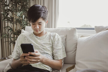 mixed Asian teen boy using smartphone at home, technology lifestyle concept