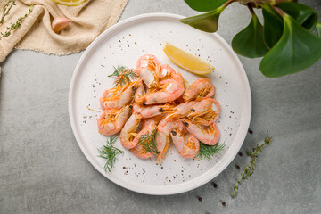 boiled shrimp with lemon on a white plate top view on grey table