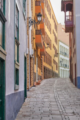 Fototapeta na wymiar Scenic street view of old vibrant historic houses, residential buildings and traditional infrastructure in alleyway road. Tourism abroad, overseas travel destination in Santa Cruz de La Palma, Spain